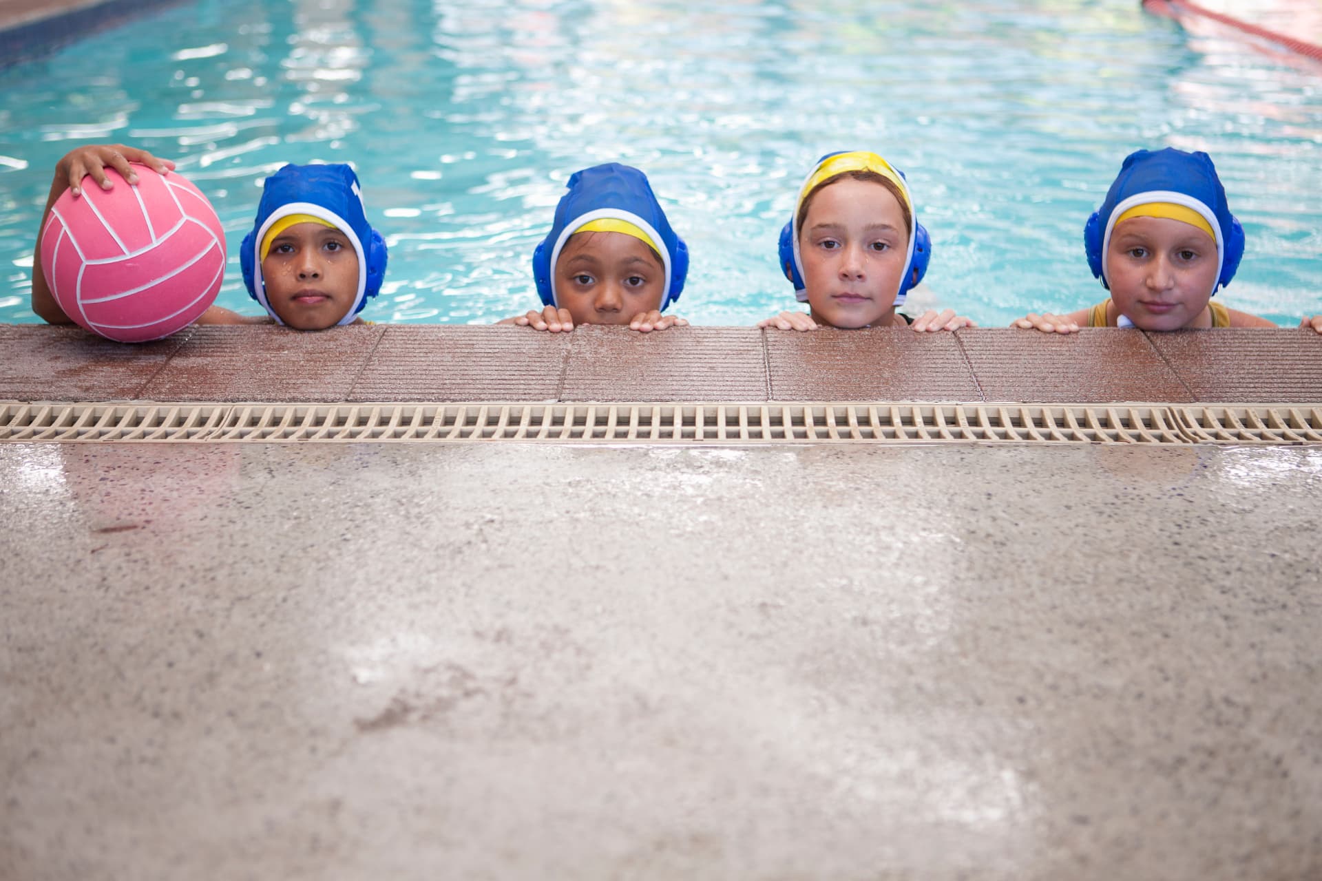 Group of young swimmers lined up at the pool wall