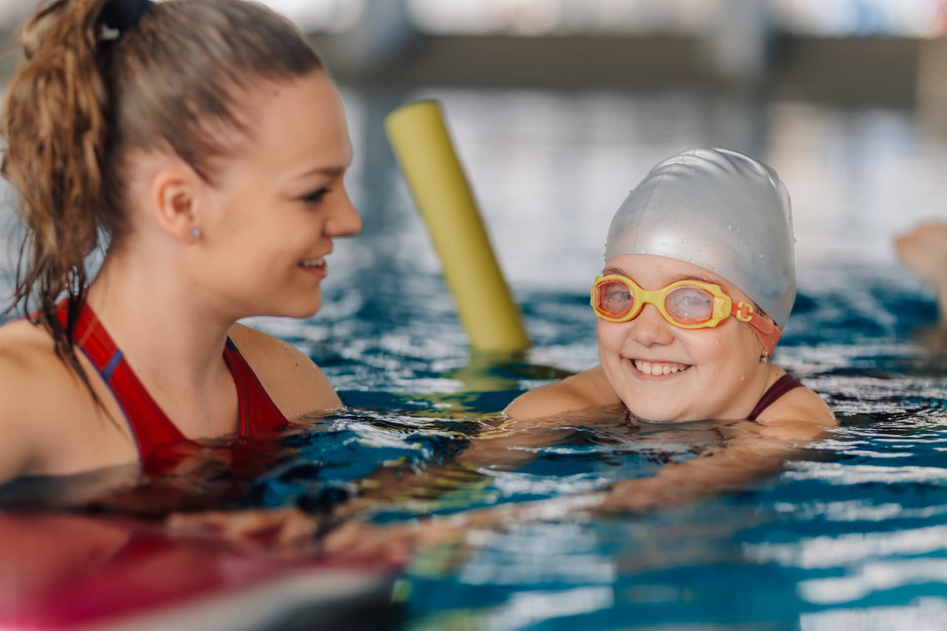 Swim instructor encouraging a smiling girl in the water
